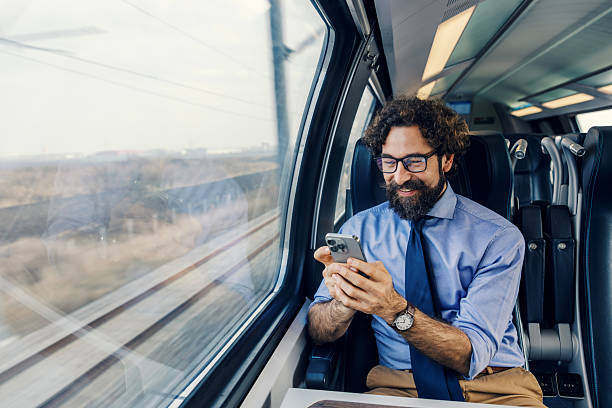 istock Businessman commuting by train smiling, using smartphone 2252692378
