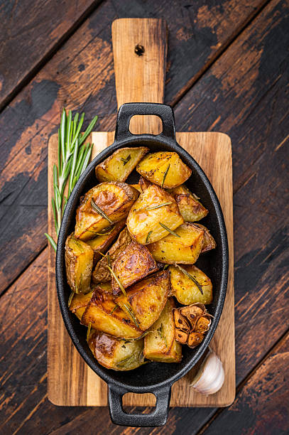 istock Baked potatoes with rosemary and garlic in cast iron pan. Simple rustic vegetable side dish overhead view 2252697361