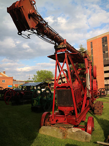 Mother and autistic teenage son examine vintage farm equipment at a country fair. They stand next to a bright red Dearborn tractor, with other antique tractors visible in the background. The scene captures a moment of shared interest and connection between parent and child, highlighting inclusive experiences for individuals with autism. The fair's agricultural heritage is on display through well-preserved machinery.