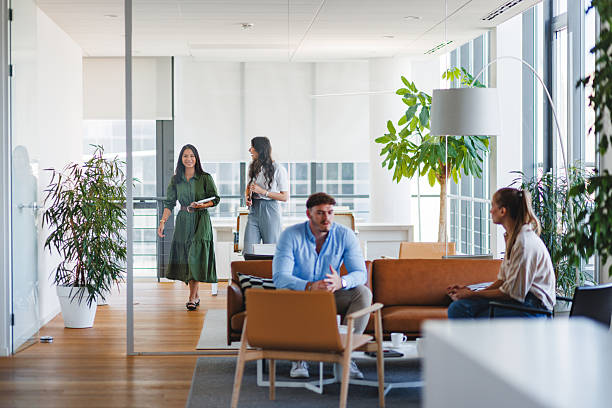 istock Young Adults Conversing in Bright Modern Office Lounge 2252700069