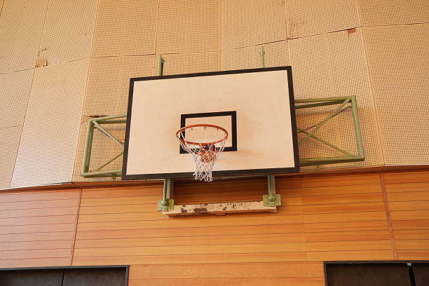 A basketball hoop is mounted on a wall. The hoop is empty and the net is down. The wall is made of wood and has a pattern