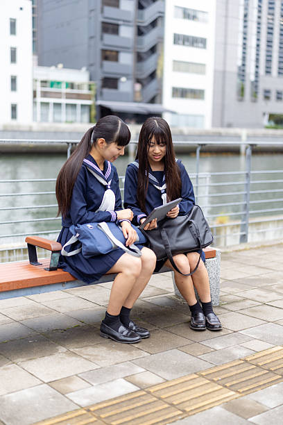 Female high school students using digital tablet in public park