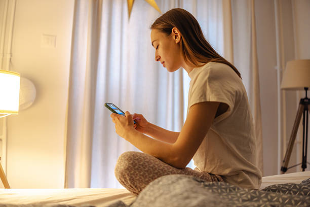 istock Young woman on bed using smartphone at night, dealing with stress and sleeplessness 2252709367