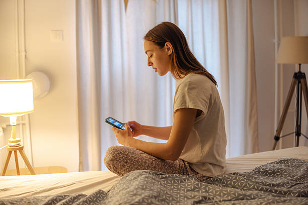 istock Young woman on bed using smartphone at night, dealing with stress and sleeplessness 2252709377