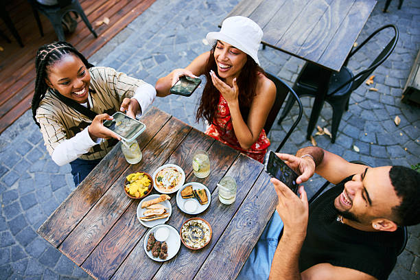 istock High angle view of Gen Z friends taking pictures while enjoying drinks and shared plates at an outdoor cafe 2252709548