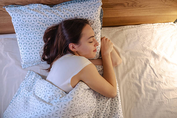 istock Young woman sleeping peacefully in a cozy bedroom on blue geometric sheets with a soft pillow, conveying calm and rest 2252709663