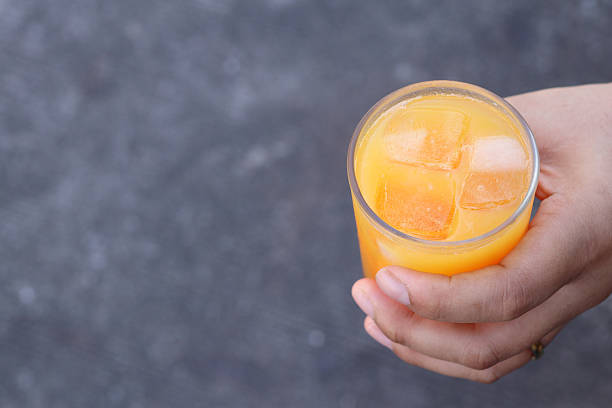 Soft drinks orange juice and iced in glass on hand