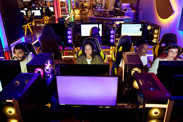 Elevated view of men and women sitting in gaming chairs, wearing headsets, smiling as they concentrate on screens.