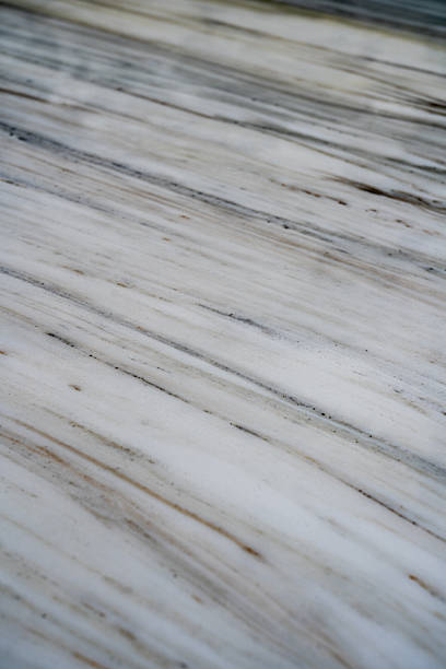 Light natural marble surface with soft linear veining, subtle grey and beige mineral streaks, smooth polished stone texture and elegant organic patterns for luxury interior design, surface backgrounds