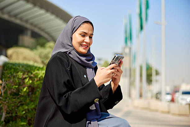 istock Young Saudi woman sitting outdoors and text messaging 2252714448