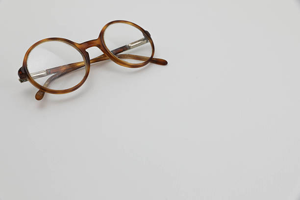 Vintage Round Eyeglasses With Worn Frame And Aged Look Placed On White Background, Symbolizing Old Glasses, Retro Style, Vision Problems, Or Senior Eyewear Concepts. Ideal Space For Adding Text Or Copy.