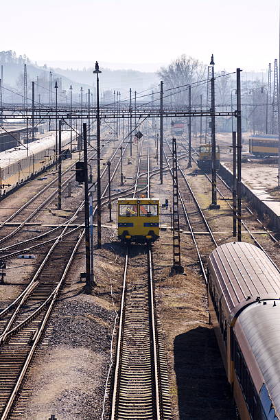 A freight train moves vehicle transport freight cars in a railyard.