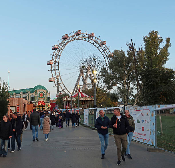 Prater Amusement Park, Vienna, Austria, October 30, 2025. Large illuminated ferris wheel.  Incidental people. Dusk, evening or twilight autumn night outdoors