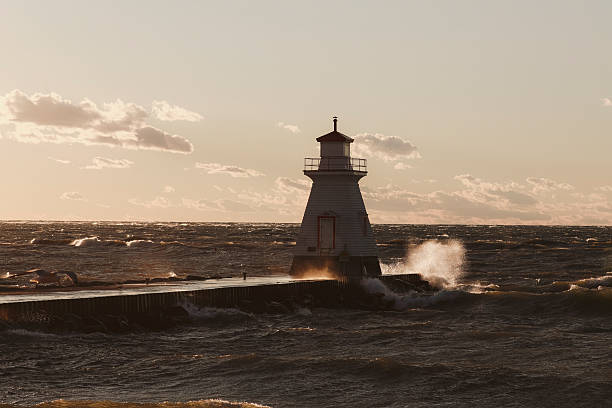 istock Lighthouse on Pier in Setting Sun and Rough Waters 2252720078