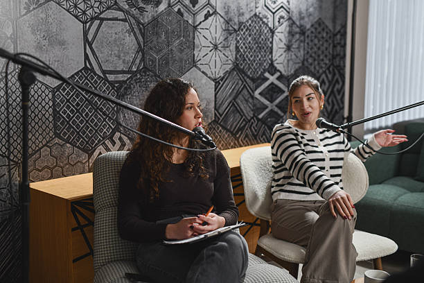 istock Two Women Conducting a Friendly Podcast Interview With Microphones and Coffee in Studio 2252721218