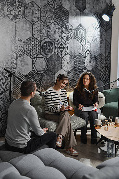 istock Casual Podcast Discussion With Microphones, Notes, And Lively Conversation In Cozy Studio Room 2252721949