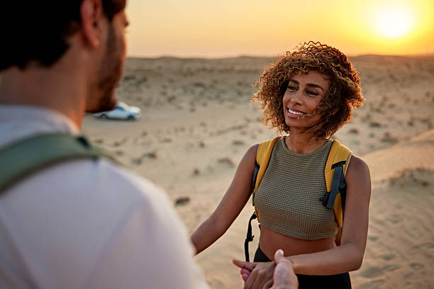 Happy couple holding hands during desert adventure at golden hour, Dubai, UAE.
