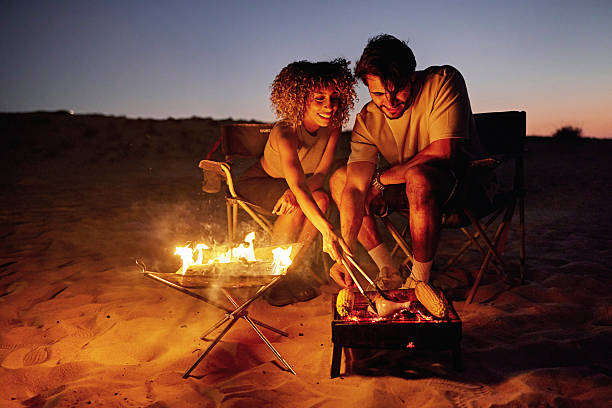 istock Couple camping, grilling food on campfire at night 2252725811