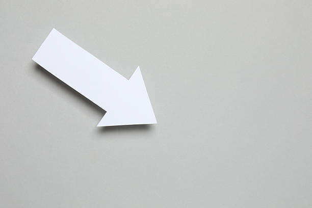 White paper arrow on grey background, top view