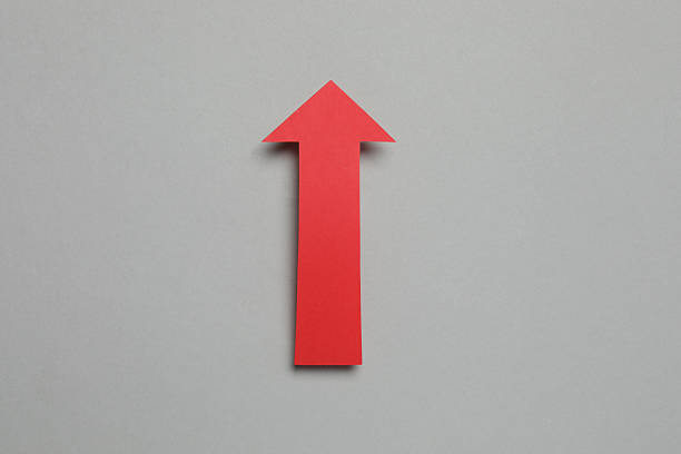 Red paper arrow on grey background, top view