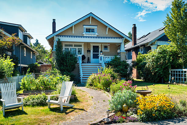 Electric car charging in front of villa with fruit trees, green lawn and sunny clear sky. Sweden.