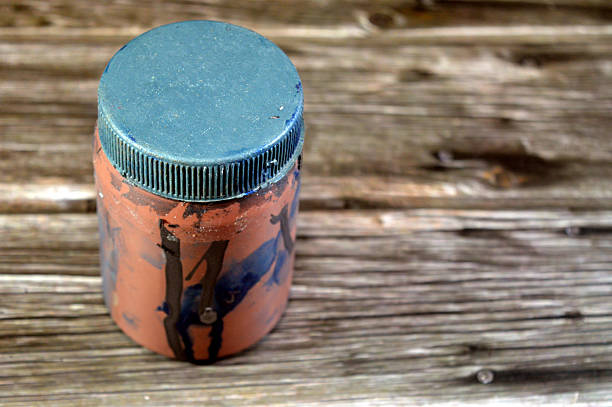 a used jar with a plastic lid, with a car paint on it, used to store car remnants of car paint liquid inside