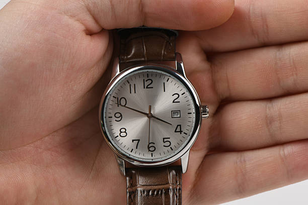 istock Male hand holding a classic silver analog watch with brown leath 2252733058
