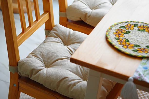 Cushioned wooden chairs circle a table with a bright placemat.