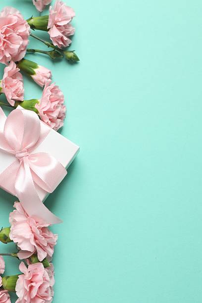 istock Beautiful bouquet of pink carnations with gift box on a colored background 2252735742