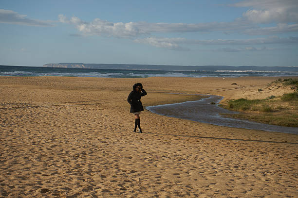 istock Woman walking on empty winter beach contemplating ocean 2252738276