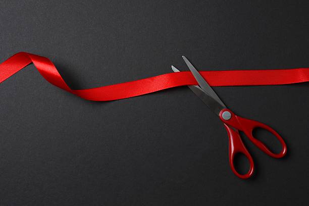 istock Beautiful red ribbon and scissors on black background, flat lay with space for text. Ceremonial tape cutting 2252738965