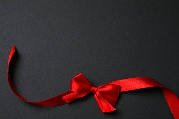 istock Red ribbon and bow on a black background, top view 2252739205