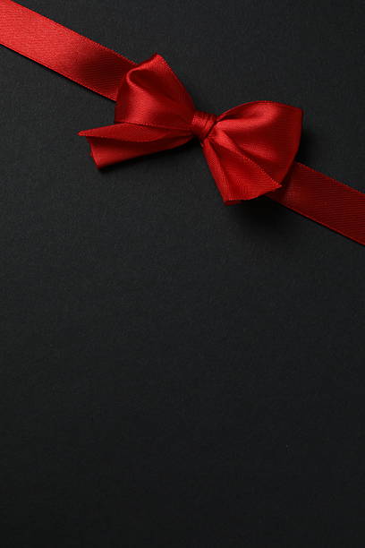 istock Red ribbon and bow on a black background, top view 2252739215