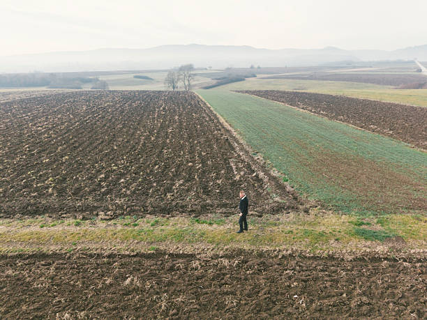 Farmer looking at his agricultural fields in winter morning