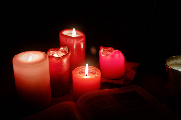Red candles glowing in the darkness creating a warm dramatic atmosphere, symbolizing hope spirituality romance and meditation for artistic and commercial use