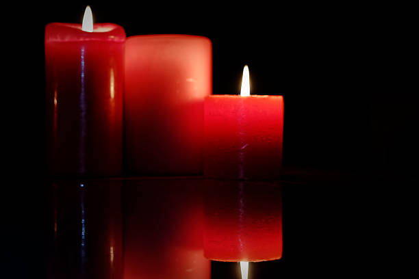 Red candles glowing in the darkness creating a warm dramatic atmosphere, symbolizing hope spirituality romance and meditation for artistic and commercial use