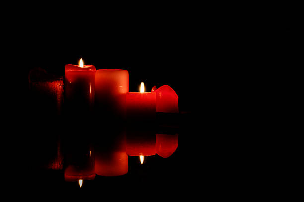 Red candles glowing in the darkness creating a warm dramatic atmosphere, symbolizing hope spirituality romance and meditation for artistic and commercial use