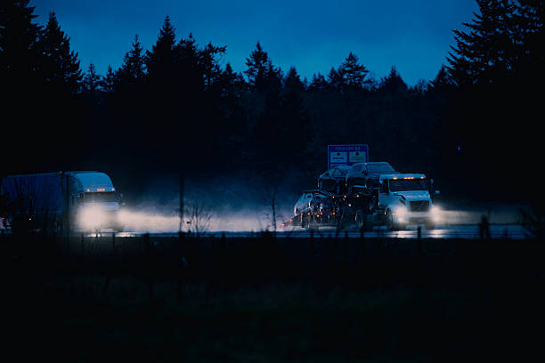 Semi-Truck with trailer on the freeway in the rain, at dusk. Headlights are on, and conditions are questionable.