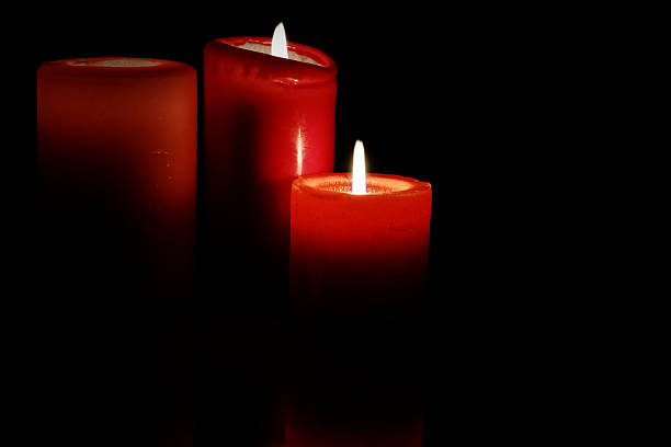 Red candles glowing in the darkness creating a warm dramatic atmosphere, symbolizing hope spirituality romance and meditation for artistic and commercial use