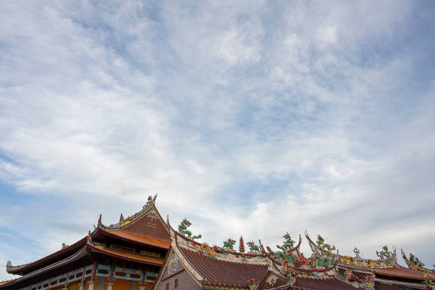 A vibrant display of traditional Chinese dragon sculptures adorning a temple roof, showcasing intricate craftsmanship against a serene sky backdrop. The scene captures cultural heritage and architectural beauty, ideal for cultural studies or travel imagery.