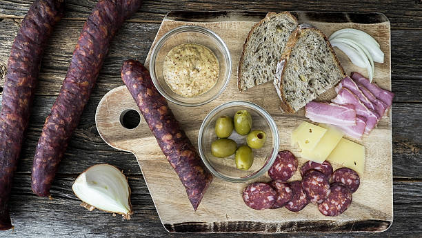 istock Sausages, cheese, and bread on a wooden board ready for sharing 2252749917