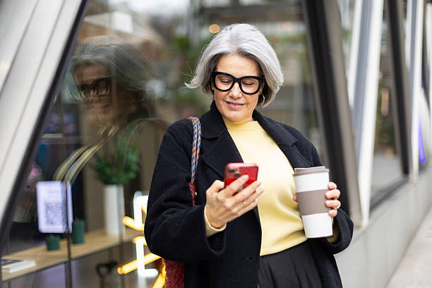 istock Mature woman using phone enjoying urban coffee break 2252757910