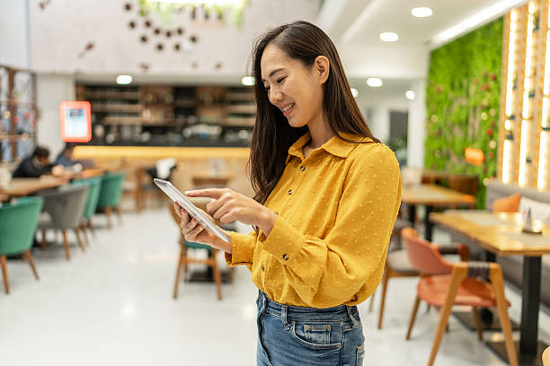 istock Young adult woman using tablet in modern restaurant 2252762531