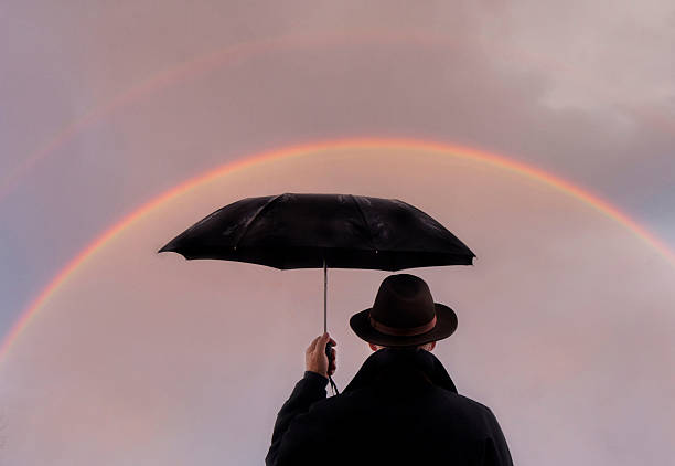 istock Man standing in the rain looking at rainbow. 2252762775
