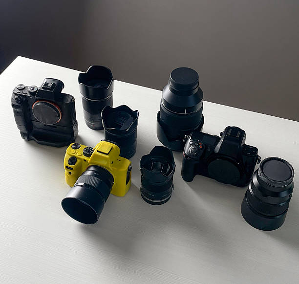 Different cameras and lenses are neatly arranged on a white table in a room.