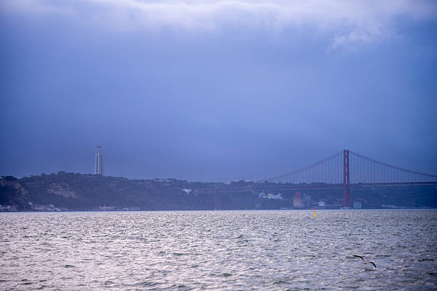 old stone column in the harbor of Praca do Comercio, Lisbon main square, with a seagull looking to the tagus river, the ships and the bridge 25 Abril
