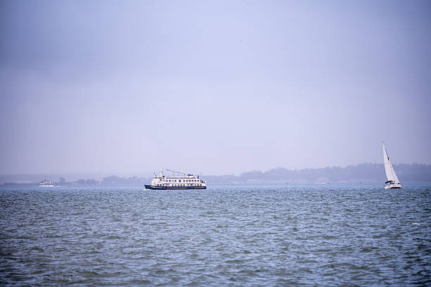 Lisbon Portugal December 05 2025. A passenger ferry and sailboat move across the Tagus River under pale light.