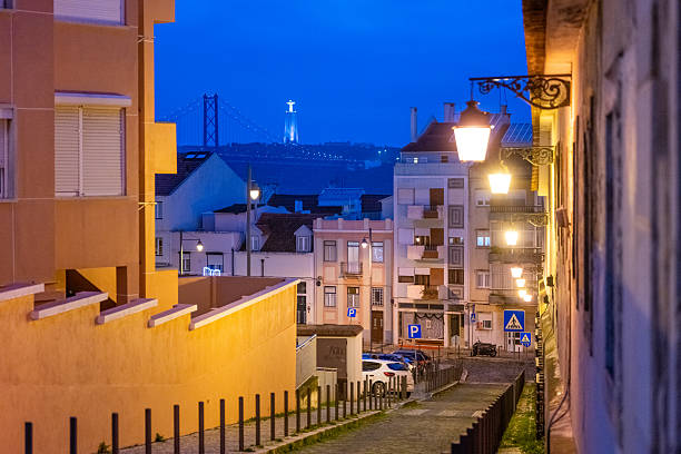 Lisbon Portugal December 05 2025. Residential hillside street lined with traditional buildings and street lamps glowing in early evening light.