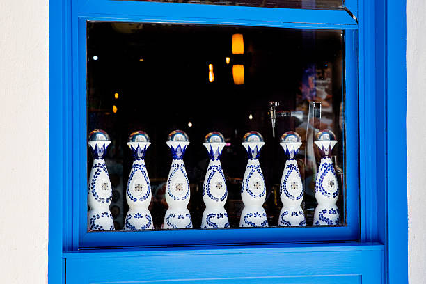 Talavera ceramic vessels for Mexican tequila. Traditional white bottles with blue pattern on windowsill. Madrid Spain 08.06.2025