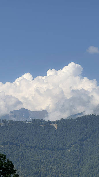 istock Fluffy white clouds float in a blue sky above lush green hills and distant mountains 2252778325